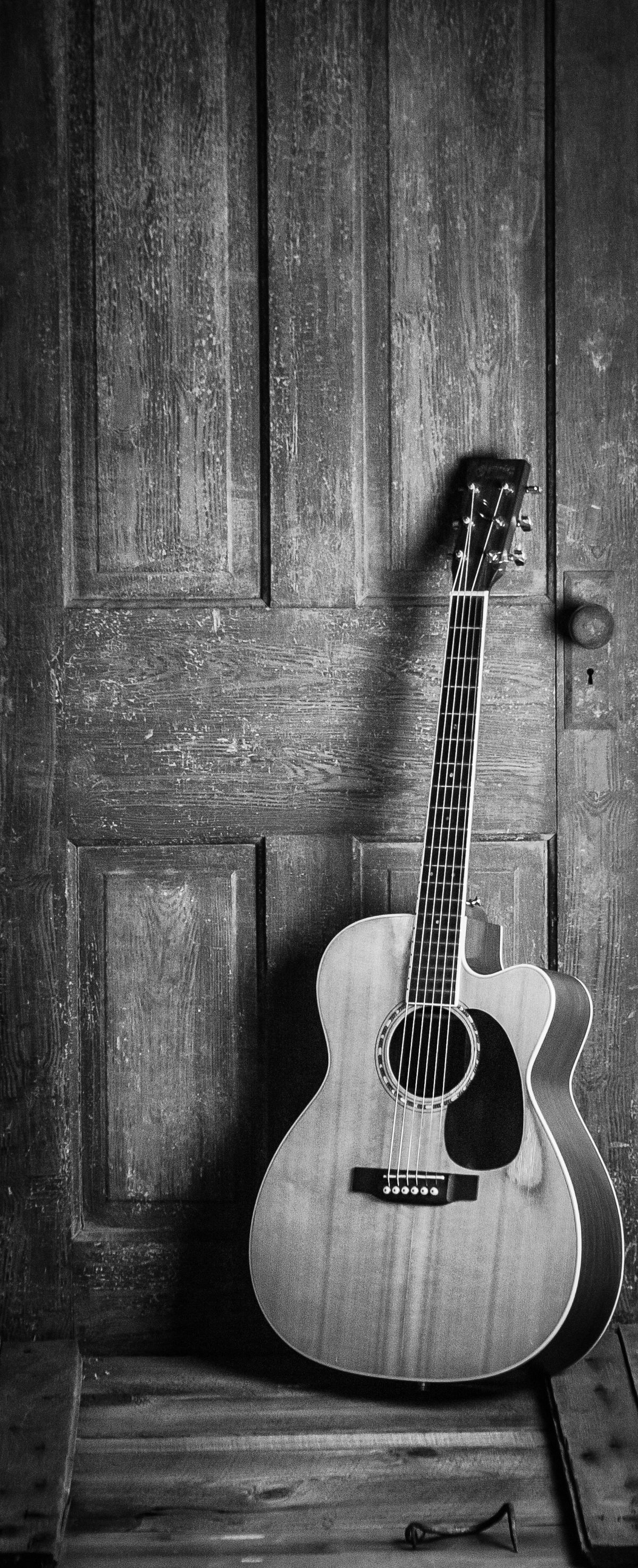Acoustic guitar resting against a wooden door